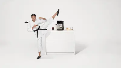 The Bosch 800 Series Fully Automatic Espresso Machine is accompanied by a martial artist performing a precise high kick. The scene emphasizes balance, precision, and quality.