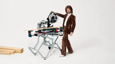 The Bosch 18V Glide Miter Saw displayed prominently with a builder in safety gear. The builder is standing beside the saw with a focused and professional demeanor, ready to demonstrate its precision.